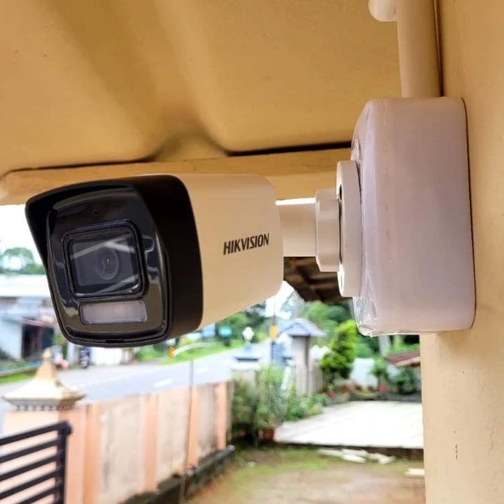 Hikvision bullet CCTV camera installed under a roof eave overlooking the street