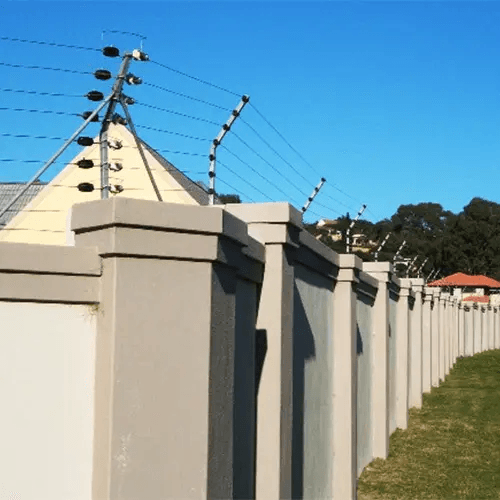 Concrete perimeter wall with multi-strand electric fencing against blue sky